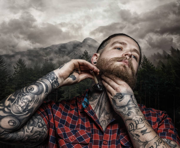 Shaving brutal tattooed male over dark forest and cloudy sky.
