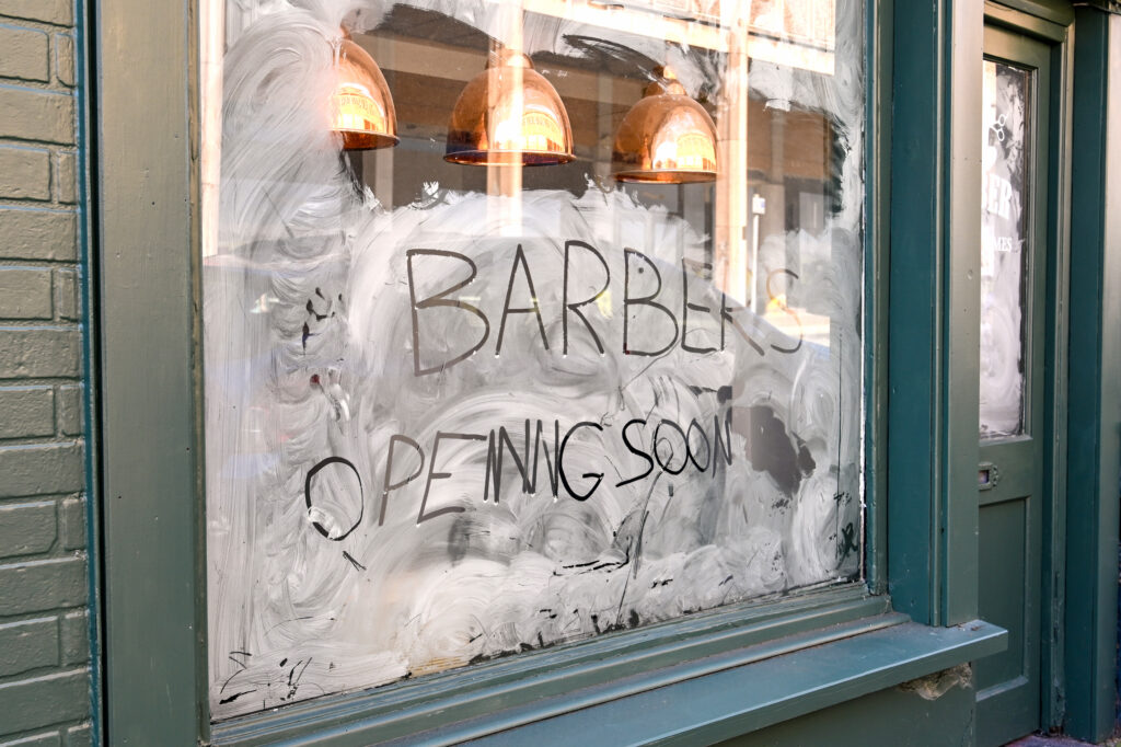 Chester, Cheshire, England - July 2021: Handwritten sign in the window of a shop in which a new barbers shop is opening