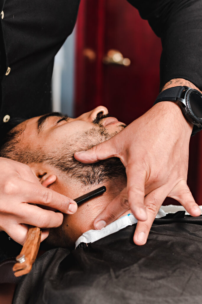 barber shaving a customer with an old shaving razor