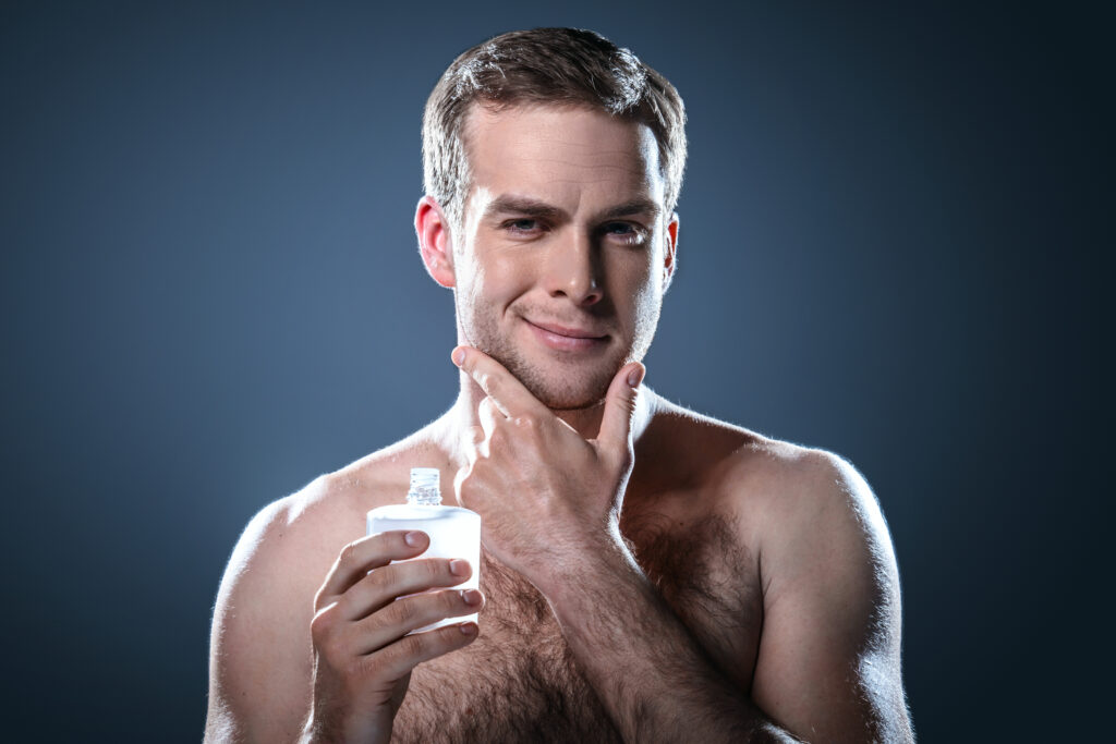 Studio portrait of handsome young man. Man with naked torso using balm after shaving